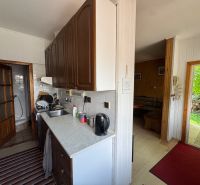 A kitchen in a family house with a bathroom, living room, and a view of the garden.