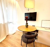 A table with a chair and a television in a studio apartment, floor with wood decor.