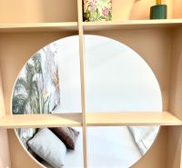 A mirror on a shelf with a book and a lamp in a studio apartment.