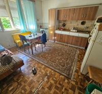 A kitchen in a family house with a dining table, kitchen unit, and floor with a wooden decor.
