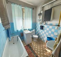 A bathroom in a family house with older light blue tiles and a bathtub.