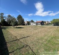 A flat plot of land in Bernolákovo with a grassy area surrounded by trees and fencing.
