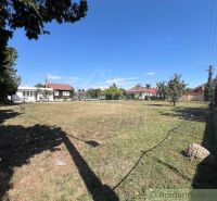 Gardens in Bernolákovo with a lawn, trees, and surrounding houses on a sunny day.