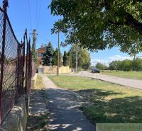 The path runs alongside the fence in the gardens of Bernolákovo, with the road in the background.