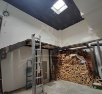 A family house with wooden beams and stored wood in the interior.