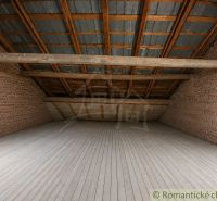 An attic room with wooden beams, brick walls, and a floor with a wooden decor.