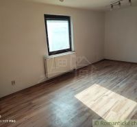 A room with a wooden decor floor and simple furniture in a family house.