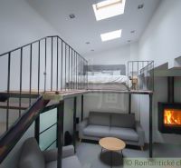 Interior of a family house with a gallery, sofa, fireplace, and bed on the upper floor.