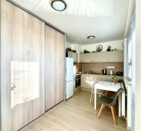 A kitchen corner with a wooden decor floor and a built-in wardrobe in a studio apartment.