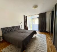Bedroom in a 4-room apartment with wood-patterned flooring, a large bed, and a wardrobe.