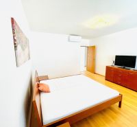 Bright bedroom in a 4-room apartment with wood-patterned flooring, a bed, and a dresser.
