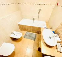 A bathroom in a 4-room apartment with a bathtub, bidet, and sink in light shades.
