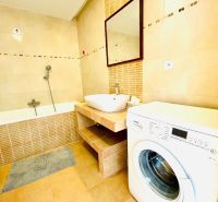 Bathroom with a bathtub and a washing machine in a 4-room apartment, floor with wood decor.