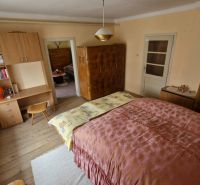 A bedroom in a family house with wooden decor and antique furniture.