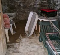 The stone cellar of a family house in Mokré Háj with stored furniture and crates.