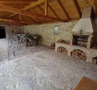 Covered seating area with a fireplace and stones in a family house, with a traditional cart and wood.