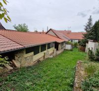 A garden at a family house in Mokré Háj with a stone wall and red roofing.