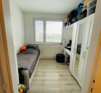 A small room in a 3-room apartment with a bed and a wardrobe, floor with wooden decor.