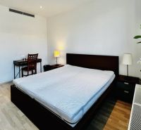 A bedroom with a large bed, a desk, and a wooden decor floor in a 3-room apartment.