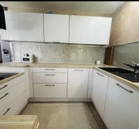 A kitchen in a 3-room apartment with white cabinets and a wooden decor countertop.