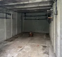 Concrete garage in Bratislava - Nové Mesto with simple walls and storage shelves.