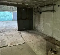 The interior of a garage with a concrete floor and metal shelves.
