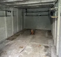 The interior of a garage with concrete walls and shelves for storage.