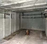 An empty concrete room with pipes and lighting, garage interior.