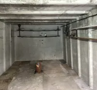 Empty concrete garage interior with shelves and lighting equipment.