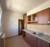 A kitchen in a 2-room apartment with ceramic tiles and wooden cabinets.