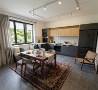 A kitchen in a family house with a dining table, dark appliances, and a large window.