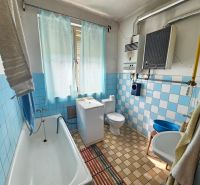 Bathroom in a family house with blue tiles, a bathtub, and a sink.