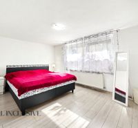 A bedroom in a family house with a red bed and a floor with a wood decor.