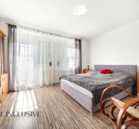 A bedroom in a family house with a wood-patterned floor, thoughtfully arranged furniture, and a rocking chair.