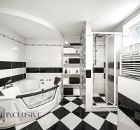 A bathroom in a family house with a hot tub, a shower, and black and white tiles.