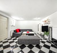 Living room in a family house with a black and white checkered floor and a gray sofa.