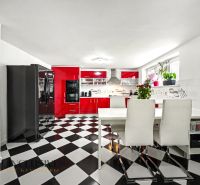A kitchen with a black and white floor and red cabinets in a family house.