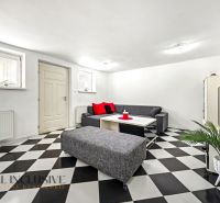 A living room in a family house with a checkered floor and gray seating furniture.