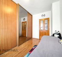 A bedroom in a family house with a wood-decorated floor and a large wardrobe with a mirror.