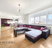 Living room in a family house with a spacious sofa and a wooden-patterned floor.