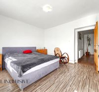 A bedroom in a family house with a comfortable bed, a rocking chair, and a floor with a wooden decor.