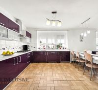 A kitchen in a family house with burgundy cabinets and a wooden decor floor.
