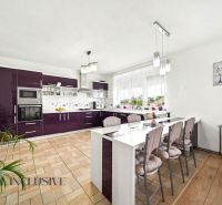 A kitchen in a family house with dark cabinets and a wood-patterned floor.