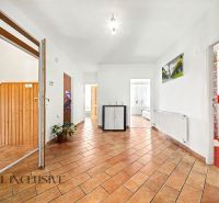 A spacious hallway with a tiled floor in a family house, featuring wooden interior elements.