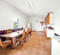 A spacious kitchen in a family house with a long dining set and tiles.
