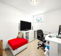 A study in a family house with white furniture and a red ottoman.