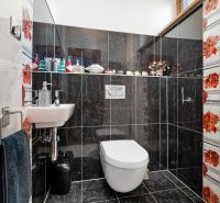 A bathroom in a family house with dark tiles and colorful floral patterns.