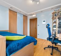 A bedroom in a family house with a wardrobe, a blue bed, trophies, and a wooden decor floor.