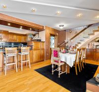 Interior of a family house with a kitchen, dining table, and wooden decor flooring.