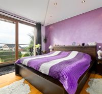 Stylish bedroom with a purple wall and a view, wooden decor flooring.
